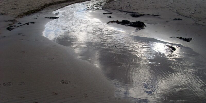 A shining stream on the sandy beach at Low Newton